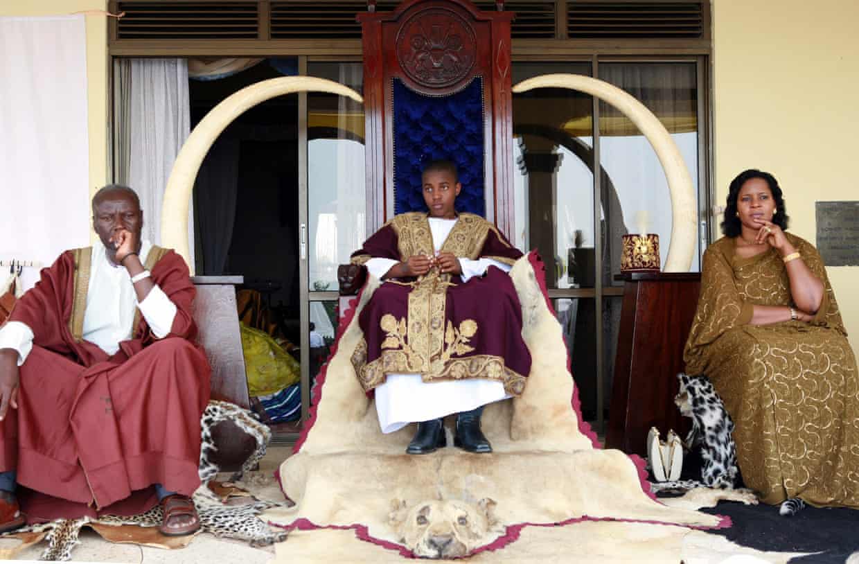 King Oyo Nyimba, aged 13, sits on a throne between his mother Best Kemigisha and an unidentified man
