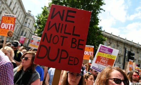 A demonstrator holds a placard reading “We Will Not be DUPed” during a protest