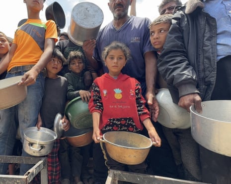 Palestinians wait for food distributed by charitable organisations in Gaza