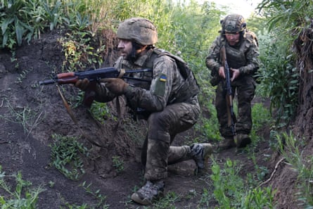 Two Ukrainian soldiers holding rifles in a trench