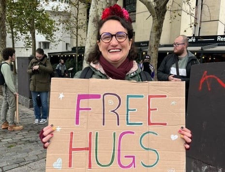 Jesse, 40, a charity worker from the north of Paris, grins and holds up a cardboard sign reading 'Free Hugs'
