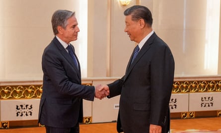 Antony Blinken and Xi Jinping, both dressed in suits, shaking hands