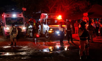 Soldiers stand near ambulances in the dark with lights on