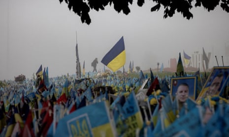 A man walks past Ukrainian flags at a memorial site commemorating fallen soldiers in Independence Square in Kyiv.