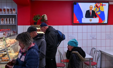 Russian President Vladimir Putin is seen on a screen at a cafe