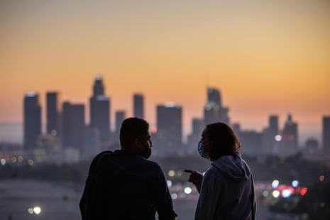 A couple wearing facemasks to prevent the spread of coronavirus watch the sunset from Elysian Park in Los Angeles, California, on November 14, 2020.