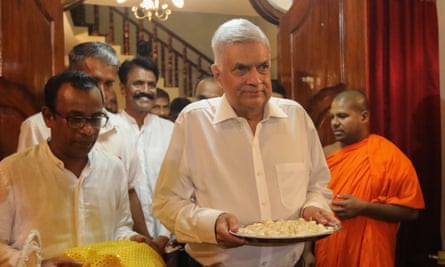 Ranil Wickremesinghe, centre, carrying a plate with an offering, was appointed on Thursday, for his sixth time as prime minister of Sri Lanka.
