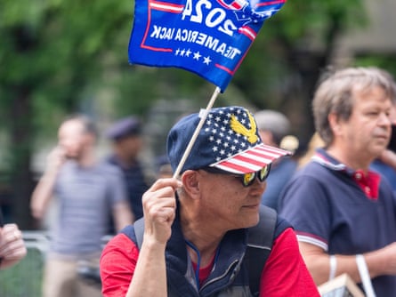 Asian middle-aged man, American flag hat, blue Trump flag.