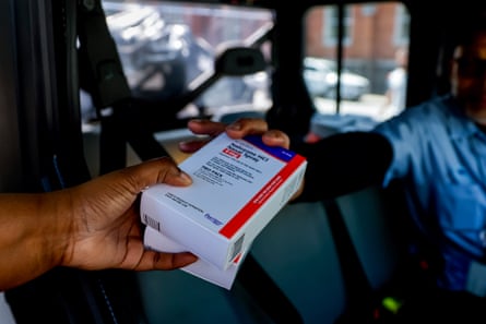 A person hands another person a box labeled ‘Naloxone nasal spray’.