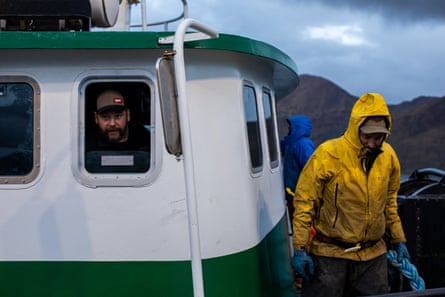 a man looks out a window as a man walks on a boat