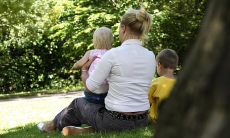 Back view of a young mother sitting in the park with two young children