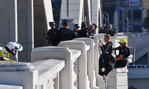 An Extinction Rebellion protestor is removed by police after abseiling off William Jolly Bridge in Brisbane on Monday.