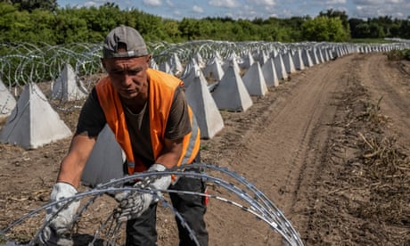 A worker and a dirt road covered in anti-tank fortifications called dragon's teeth due to their pyramid shape