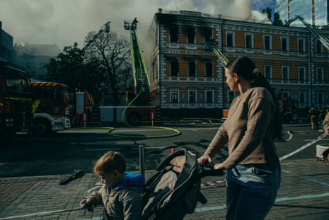 Mother with a child passing by the site of the Russian drone hit in Kyiv city centre on 28 September.