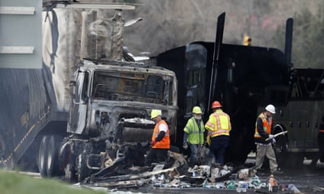 Emergency workers clear debris from a charred semi-trailer after a deadly pileup caused four deaths on Interstate 70 west of Denver.