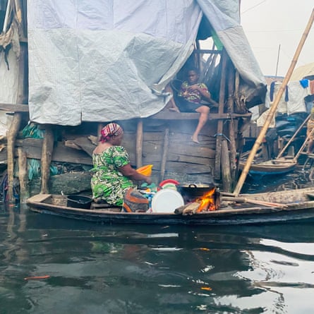 ‘They told us to leave. They didn’t tell us where to go’: the demolitions destroying homes and lives in Lagos A woman cooks over an open fire in a canoe next to a wooden shack covered in waterproof sheets, in which a boy sits with his legs dangling over the side