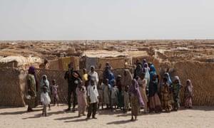 Displaced families stand at the main gate of a camp for internally displaced people at Monguno, Borno state