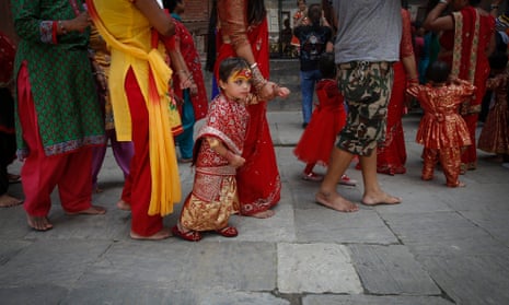 A girl in traditional attire walks with her mother during a ceremony in Kathmandu