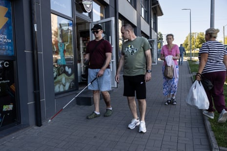 Ivan Rozuman, using a cane, walks down a street beside another man