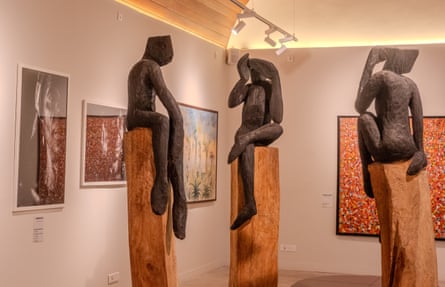 Sculptures of figures sitting on wooden posts.