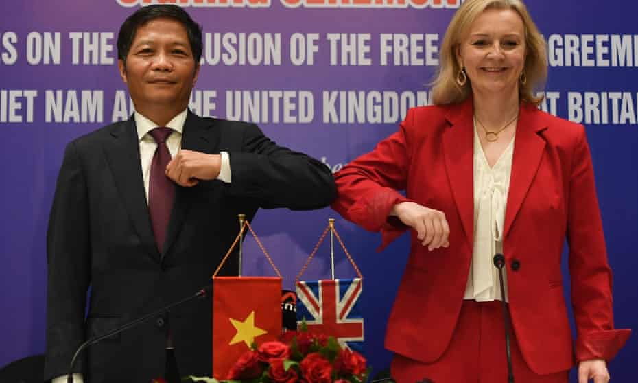 Liz Truss elbow bumps Vietnam’s minister of industry and trade, Tran Tuan Anh, after signing a free trade agreement in Hanoi in December.