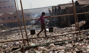 A man crosses a bridge over a trash-filled canal in the Hazaribagh neighborhood of Dhaka, Bangladesh.