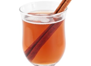 Glass mug of hot apple cider with a cinnamon stick, on white background