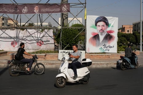 People drive past a banner showing a portrait of Mojtaba Khamenei in downtown Tehran.