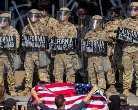 Protester holds up US flag in front of a line of national guard troops