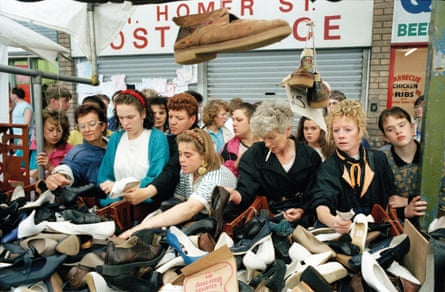 A 1990 photo by Tom Wood showing women looking through shoes on a market stall.