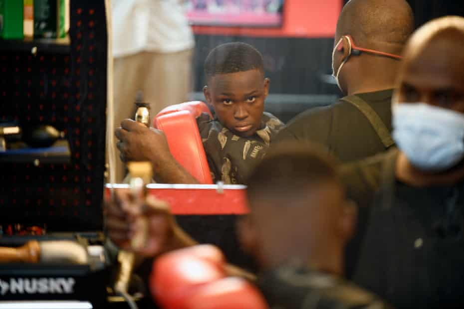 Camden Woods, 13, checks his haircut at Thomas’s barber shop. Woods is vaccinated.