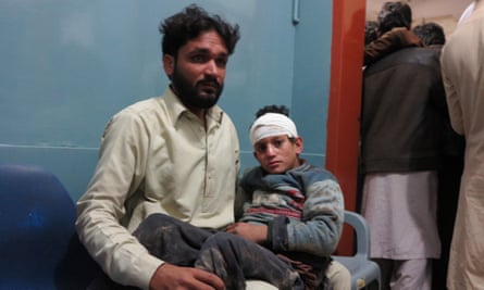 A man holds his injured son as they wait for treatment at a hospital in Mingora, Pakistan.