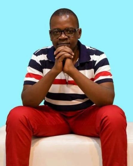 Amerix looks directly at the camera with hands folded under his chin.