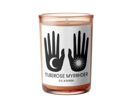 A D. S. & Durga TUBEROSE MYRRHDER candle in a dark orange glass jar. The label on the front of the jar is white. It has two hand silhouettes. One has a moon in the palm, the other a sun graphic. The Candle scent – TUBEROSE MYRRHDER is also displayed.