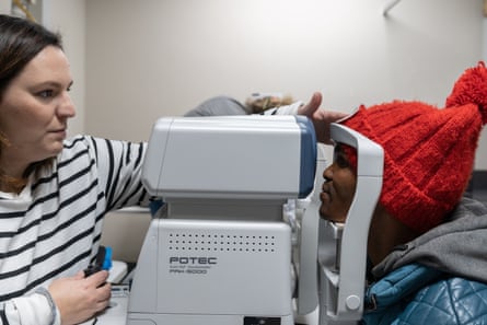 A woman looks through a machine at a man’s eyes