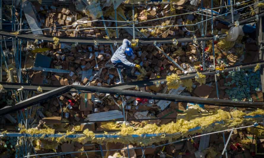 A man searches for victims while climbing through the collapsed roof of a Mayfield Consumer Products candle factory in the aftermath of a tornado in Mayfield, Kentucky.