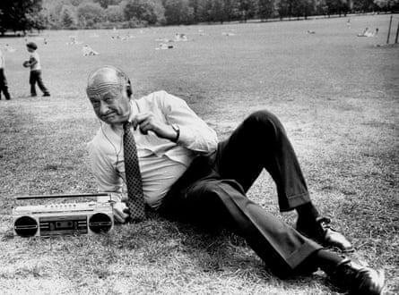 black and white photo of man in shirt and tie lying next to radio on grass