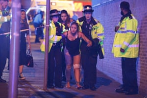 Police and other emergency services are seen helping a woman injured in the attack outside the Manchester Arena