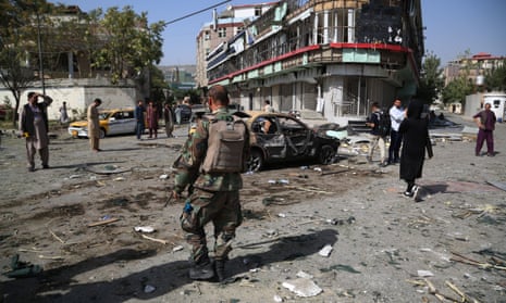 A soldier and residents among debris in the street after a car-bomb attack