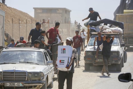 Palestinians flock to the area where aircrafts drop humanitarian aid supplies via parachutes in Deir al Balah, Gaza on August 20, 2025.