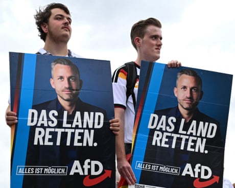Two young men hold up two placards featuring the AfD's Ulrich Siegmund and the words 'Das Land Retten' - German for 'Save the Country'.