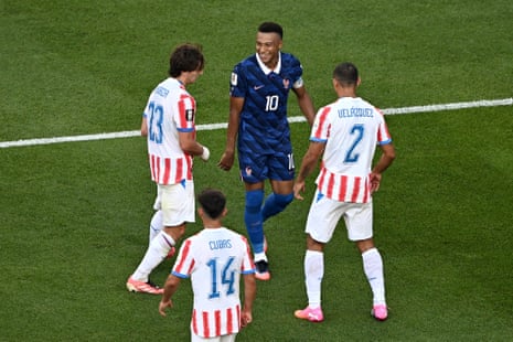 Kylian Mbappe smiles next to Paraguay players