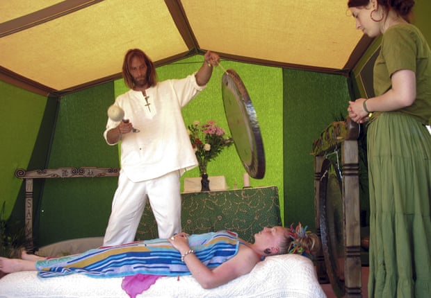 a client undergoes a gong bath cleansing ritual at a Festival in Somerset, Britain