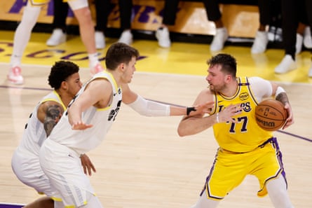 The Lakers’ Luka Doncic, right, protects the ball from Jazz center Walker Kessler and guard Keyonte George on Monday.
