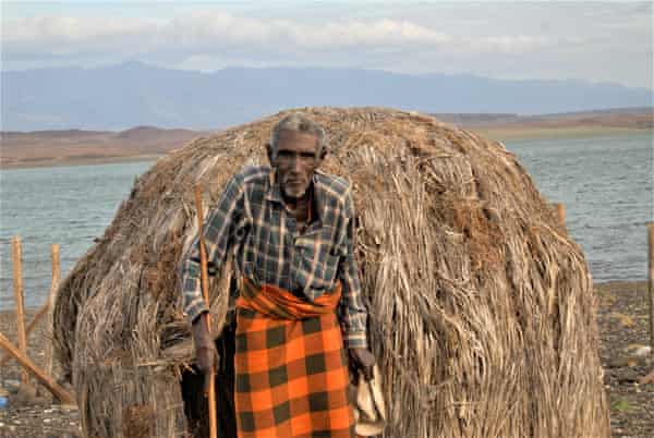 Mombasa Lenapir, an El Molo elder, stands next to a rock shrine on the shores of a lake