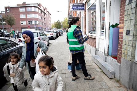 Council volunteers knock on a door as a mother and her children walk by in the street