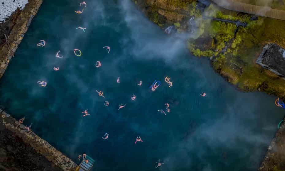 Aerial shot of people swimming in a natural hot spring: The Secret Lagoon, Fludir, Iceland
