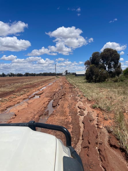 A red dirt road with deep rivets filled with water