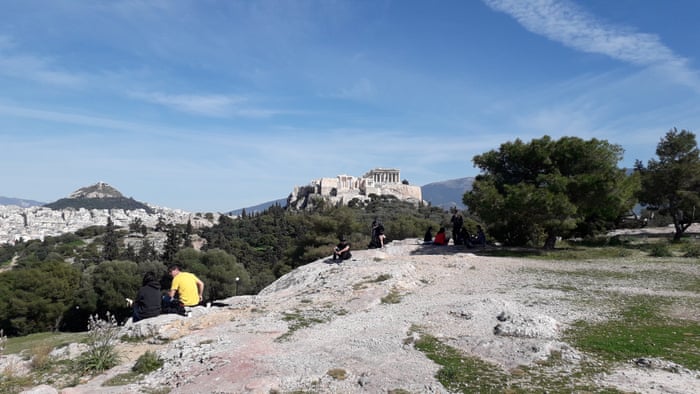 In a first, the 5th century BC Acropolis is closed. With few other places to go, Athenians take in the site on rocks beneath the ancient site.