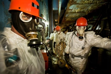 Workers wearing respirators, hard hats and plastic suits